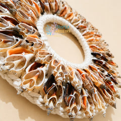 A handmade circular bag or wreath made from numerous natural seashells arranged around a thick white rope base, photographed on a plain beige background. A semi-transparent 'ROPEA ARTistry' watermark is visible in the center.