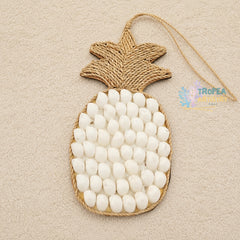 A pineapple-shaped wall hanging or ornament made from natural jute rope and white oval stones, photographed on a light beige textured background.
