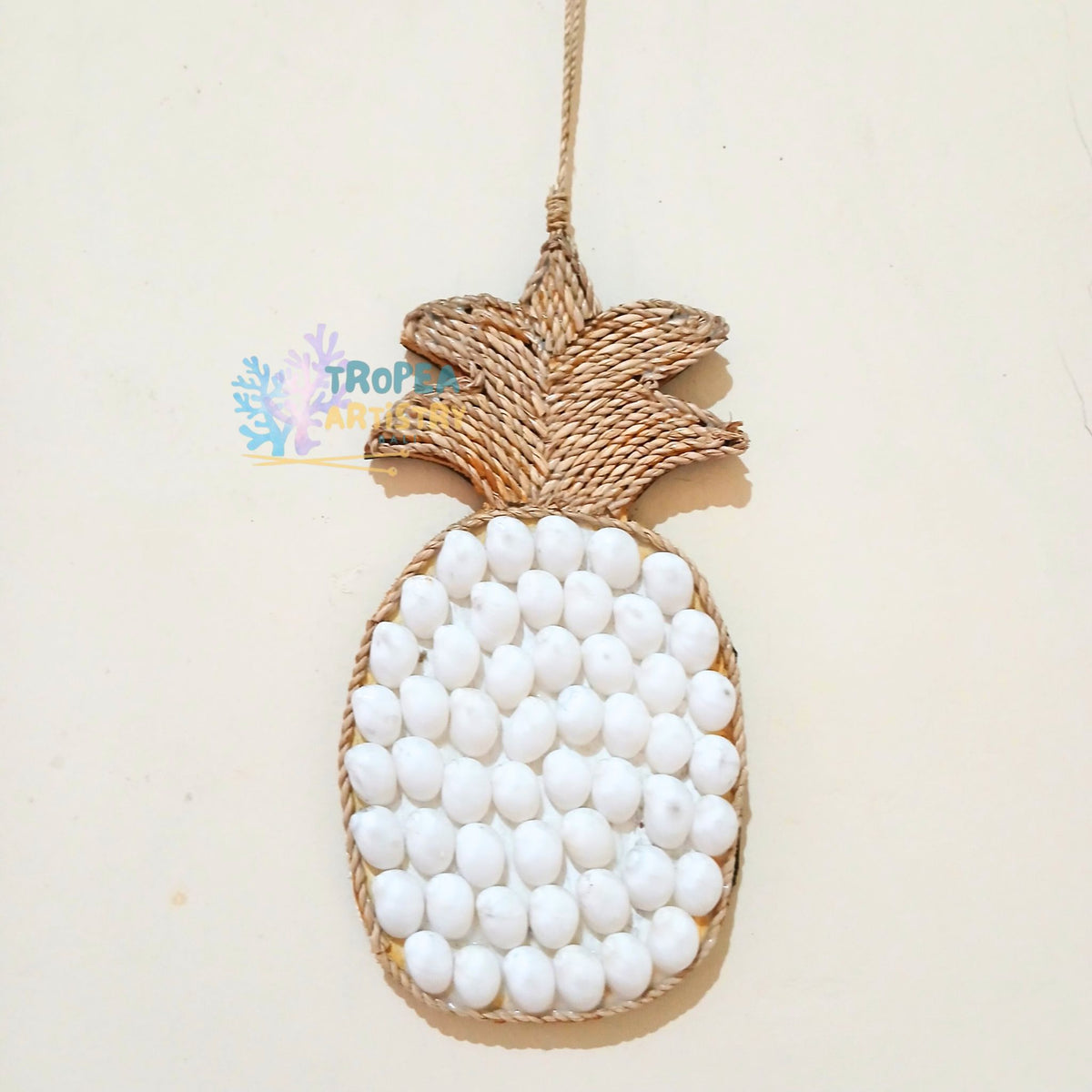 A pineapple-shaped hanging ornament made from natural woven jute rope and covered with small white beads, shown against a plain off-white background.