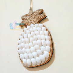 A pineapple-shaped decorative wall hanging or ornament made from natural jute rope and covered with many small white egg-shaped embellishments, shown against a plain light beige background.