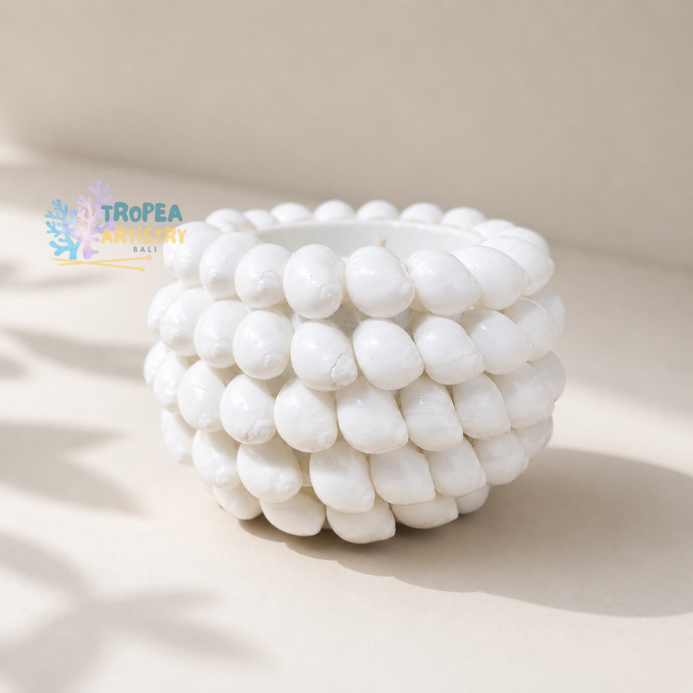 A white ceramic planter made of stacked, rounded teardrop-shaped beads, photographed on a warm beige background with soft shadows. A 'TROPSEA ARTistry BAY' logo is visible in the upper left.