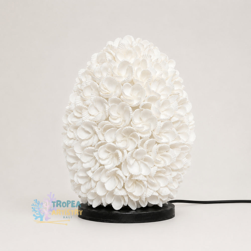 A white coral-like decorative lamp or sculpture with a textured, layered petal or flower surface, mounted on a round black base with a visible black power cord, photographed against a plain light background.