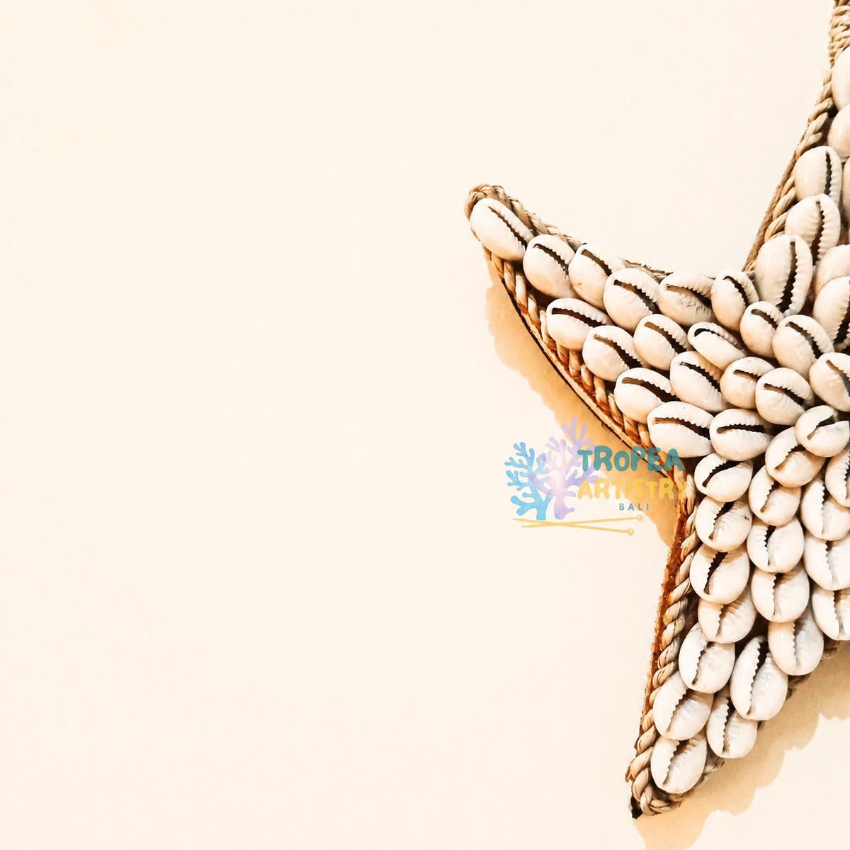 A decorative starfish made from small white seashells with dark lines, attached to a rope, photographed on a warm off-white background. A small tropical watermark is visible near the center.