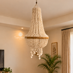 A large bohemian-style chandelier with cream-colored glass beads and a natural rattan band, hanging in a warm, beige-toned living room.
